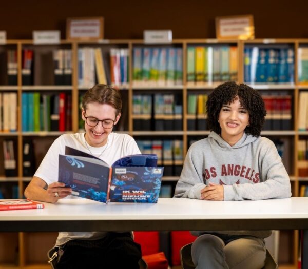 Twee studenten zitten naast elkaar en lezen een boek